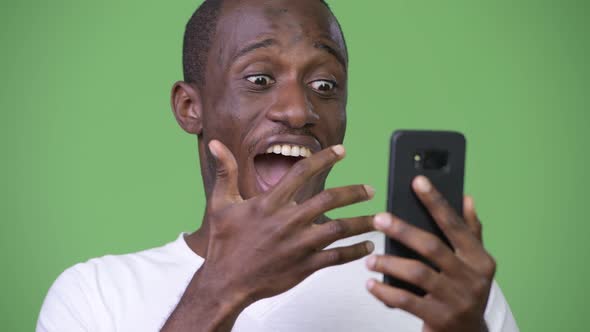 Young Happy African Man Looking Shocked While Using Phone