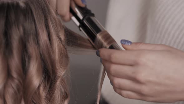 Closeup of the Stylist Performs a Curl of Light Hair