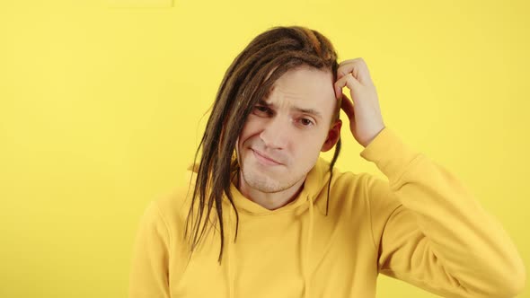 Young Thoughtful Man Scratching Head on Yellow Background