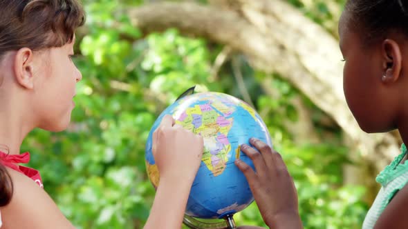 Schoolkids looking at globe in campus at school