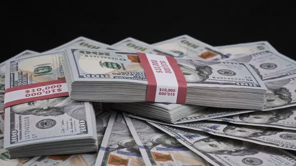 Bundles of Dollars Lying on a Pile of Money and Rotate on Black Background