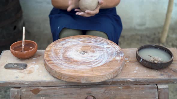 Woman Potter Works with Red Clay on a Potter's Wheel in the Workshop