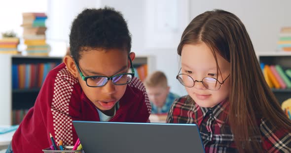 Two Preteen Diverse Students Using Laptop in Classroom