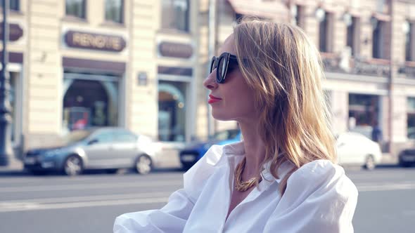 Woman in Sunglasses with Take Away Coffee Catching a Taxi in the City