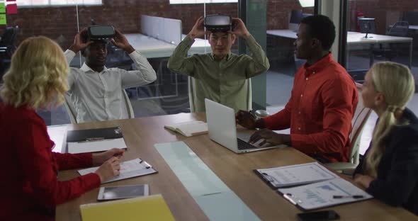 Diverse group of business colleagues sitting in meeting room using vr headset applauding