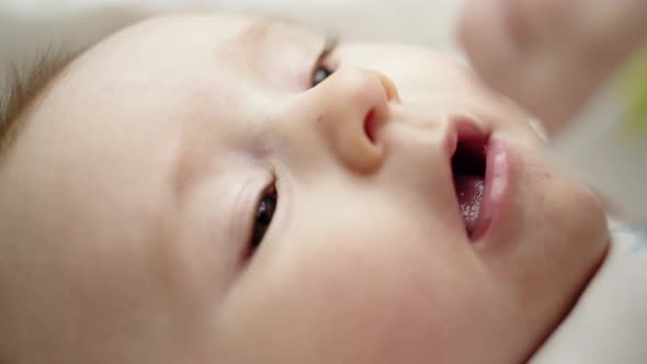 Close Up on the Face of an Adorable Newborn Baby Lying on a Blanket Moving Its Hands Across