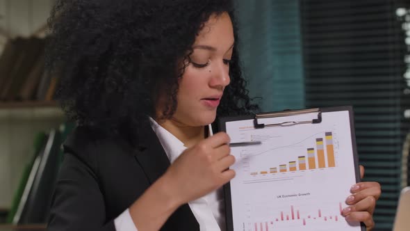 Portrait of African American Woman is Talks on Video Conference on Laptop and Demonstrates Graphs