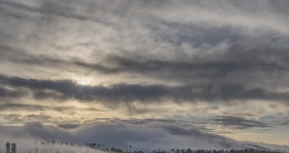 Timelapse of Evening Sun Rays Emerging Through the Cold Foggy Clouds in the Mountains. Sunset in