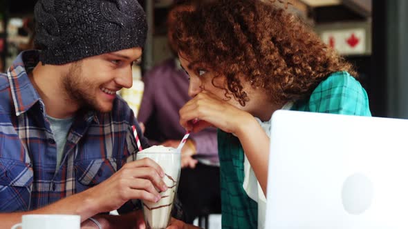 Couple drinking smoothie together with straw in pub