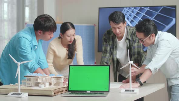Green Screen Laptop On The Table While Asian Engineers Group Discussing About Work On The Blueprint
