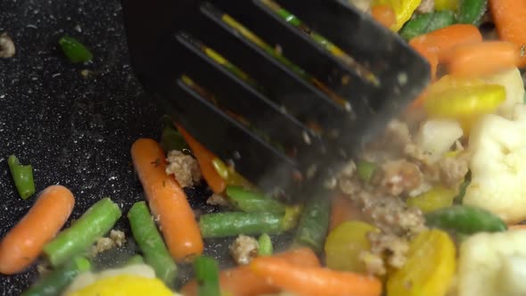 Close up view of steaming frying pan and mixed vegetables with frying minced