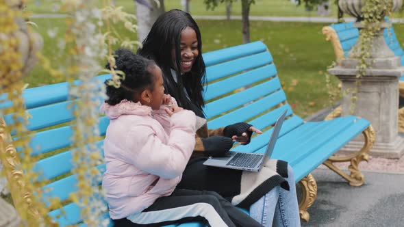 Happy African American Family Use Laptop Young Mother with Little Daughter Communicate Sitting on