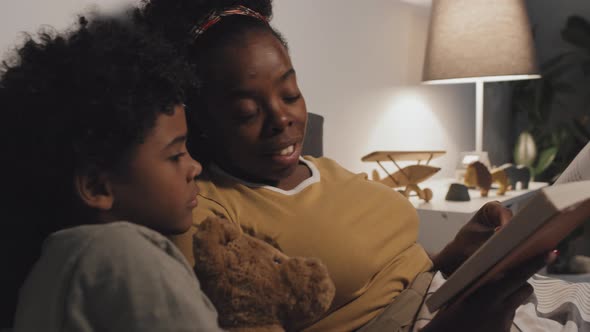 Mom Reading Book to Boy in Bed