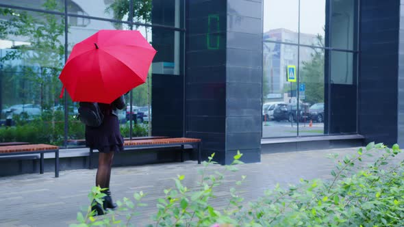 Girl with Red Umbrella Goes Along Urban Street