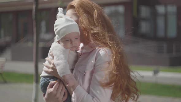 Portrait Young Cute Beautiful Redhead Mother Holding a Adorable Baby in Her Arms and Talking To Him