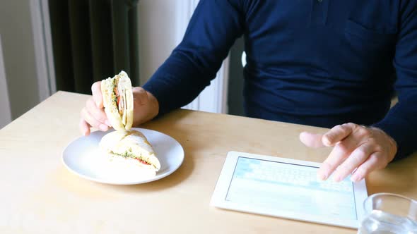Man using digital tablet while having breakfast in living room 4k