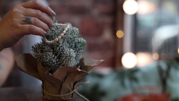 Woman Decorates a Decorative Christmas Tree Standing on the Table at Home