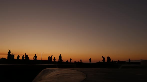 Silhouette of Young Jumping Skateboarder Riding Longboard, Summer Sunset Background. Venice Ocean