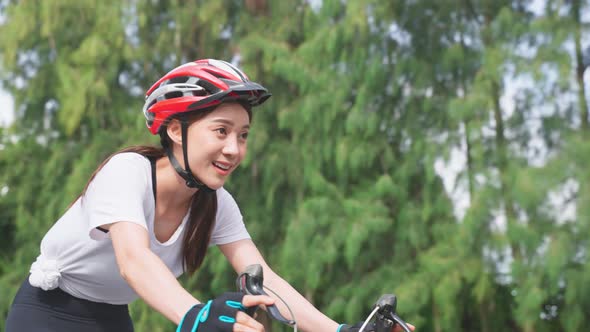 Asian young beautiful sport woman exercise workout by riding bicycle for health in public park.