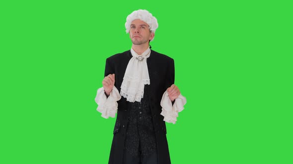 Man Dressed in Courtier Frock Coat and White Wig Thinking and Fidgeting with His Fingers on a Green