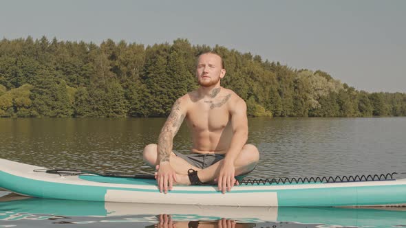 Man Meditating on Sup Board in Lake