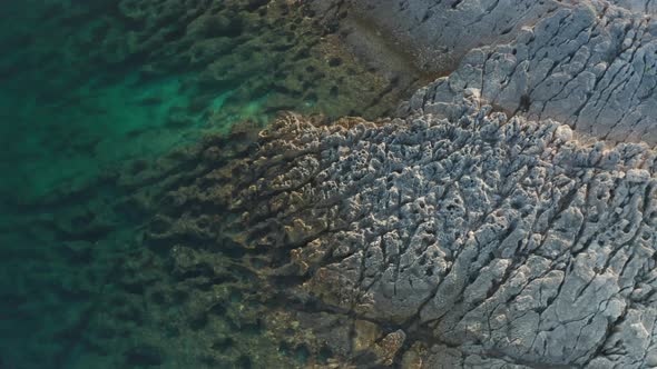 Aerial parallax shot of a rocky coastline. Alabaster rocks deformed by the water. Top down shot, cam