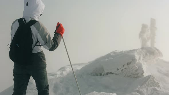 A Young Woman is Walking on the Top of a Snowcapped Mountain