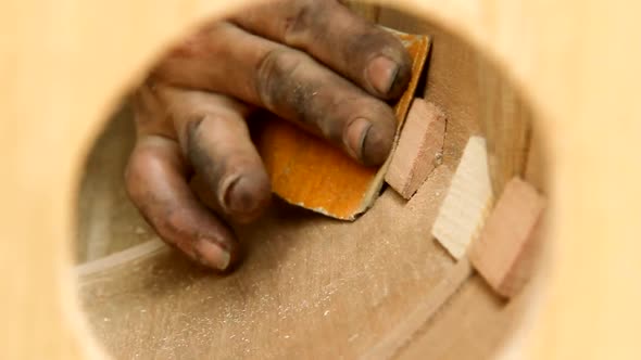 Harpmaker Sanding the Wood of a Harp in Progress in his Workshop.