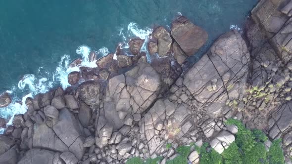 Waving Ocean at Shore with Huge Grey Stones and Green Bushes