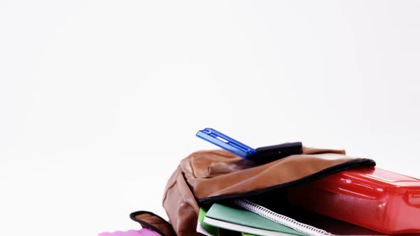 Schoolbag with various supplies on white background