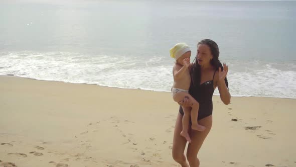 Mom with a Two-year-old Daughter Walking Along the Sandy Beach