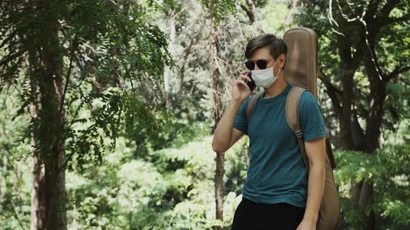 Man Is Walking in the Park and Talking on Phone