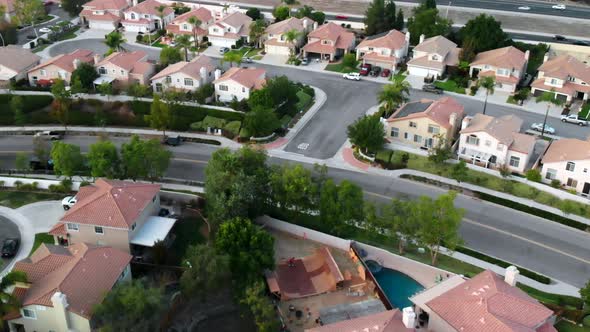 Aerial shot of a giant wooden skateboard half pipe built in a residential backyard with skaters.