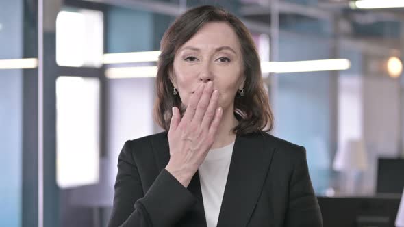 Portrait of Attractive Middle Aged Businesswoman Giving Flying Kiss and Looking at Camera