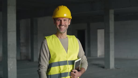 Portrait of caucasian engineer holding digital tablet while standing on construction site.