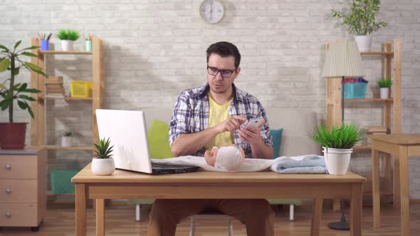 a Young Future Father Learns To Swaddle a Child Holding a Smartphone in His Hand and a Doll