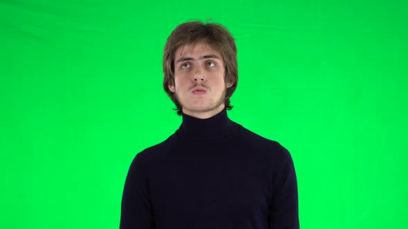 Portrait of Tall Slender Young Guy with Thick Hair Is Waiting on a Green Screen