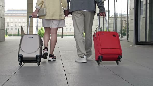 Couple with Suitcases Walking Through the Airport or Train Station