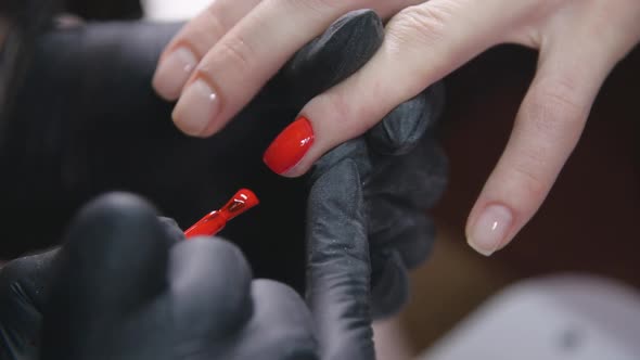 Hands of a Woman Applying Red Nail Polish in a Beauty Salon