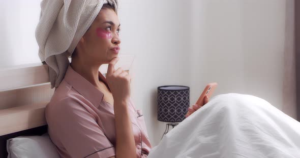 Woman in Pajamas with a Towel on Head and Patches is Planning a Henparty