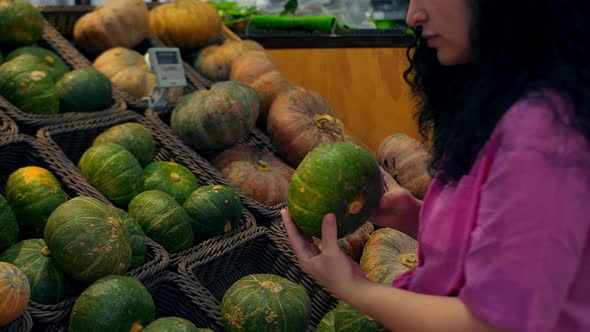 Woman Buys Groceries Chooses a Pumpkin in the Supermarket for a Hollowin Holiday