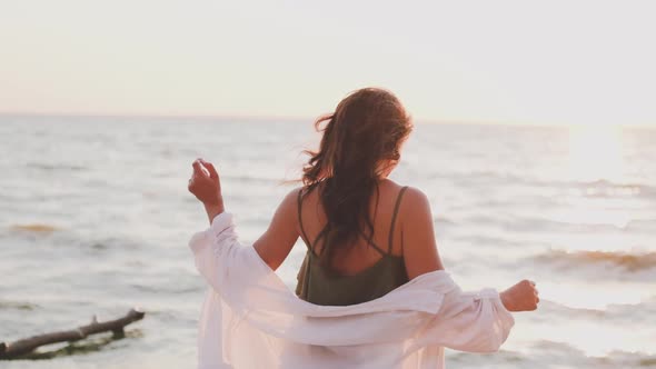 Beautiful Girl Dancing on the Beach in a White Shirt. Free Girl with Long Hair in a White Shirt