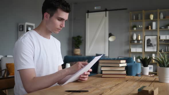 Young Man Reading Documents Going Through Contract