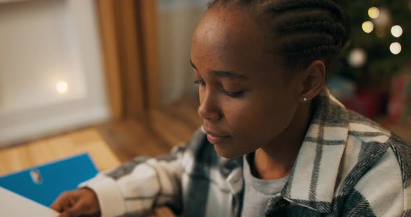 Attractive Girl of African Appearance Sitting at Table in the Living Room alt