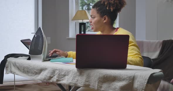 Busy Hurrying African American Woman Messaging Online on Laptop and Tablet with Stressed Facial