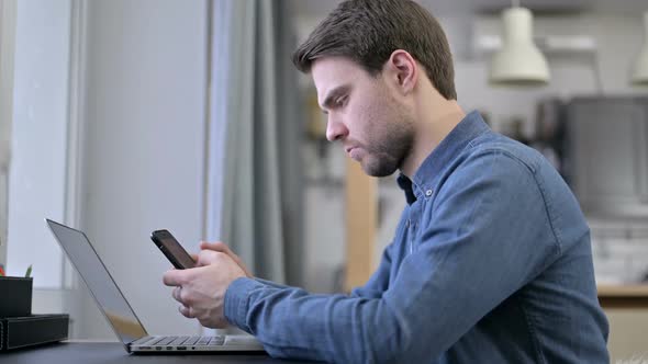 Beard Young Man Using Smartphone and Laptop