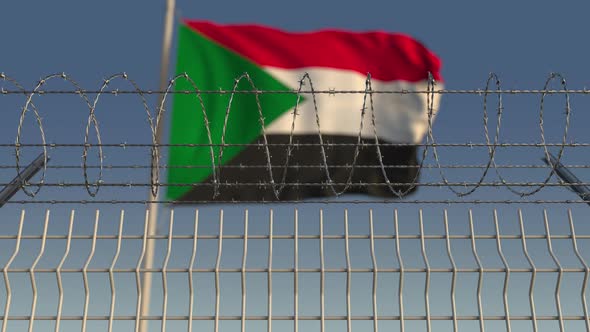 Waving Flag of Sudan Behind Barbed Wire