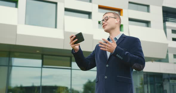 A Businessman Is Standing Near a Business Center and Talking Emotionally Over a Video Link