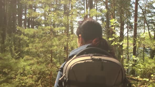 Hiking Woman Walk with a Hiking Backpack in Spring Green Forest