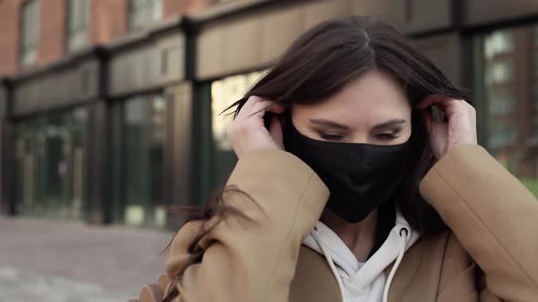 Nice Girl Brunette Puts on Black Virus Mask on Her Face